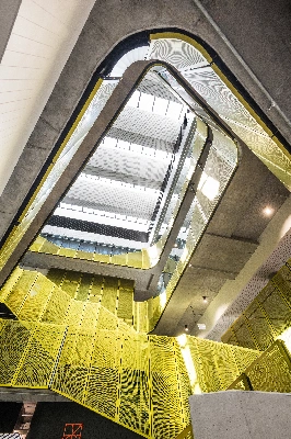 A modern, yellow spiral staircase viewed from below.